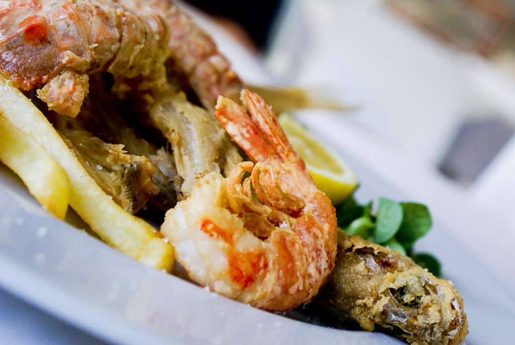 Delicious fried seafood with fries, lemon wedge, and greens on a plate.